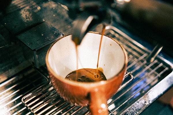 An image of a cup under a coffee machine.